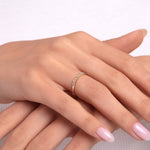 Model wearing a delicate 14K gold ring with small round diamonds on a thin band