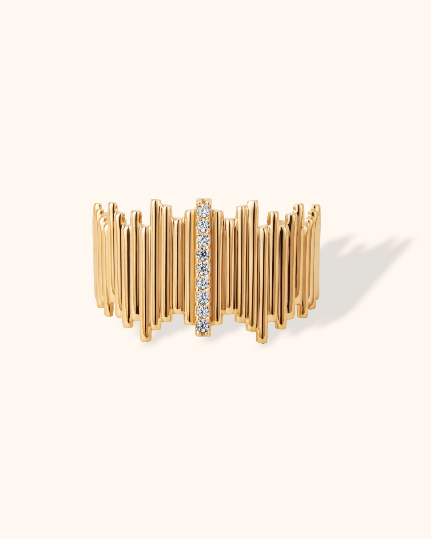 14K yellow gold ring with textured vertical design and central row of white diamonds on cream background.