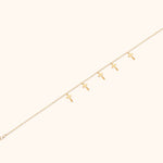 Minimalist bracelet with six cross charms crafted in 14K gold, displayed on a neutral background