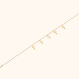 Minimalist bracelet with six cross charms crafted in 14K gold, displayed on a neutral background