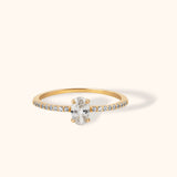 Elegant 14K gold ring featuring an oval cut white center stone with pavé side accents on a slim band