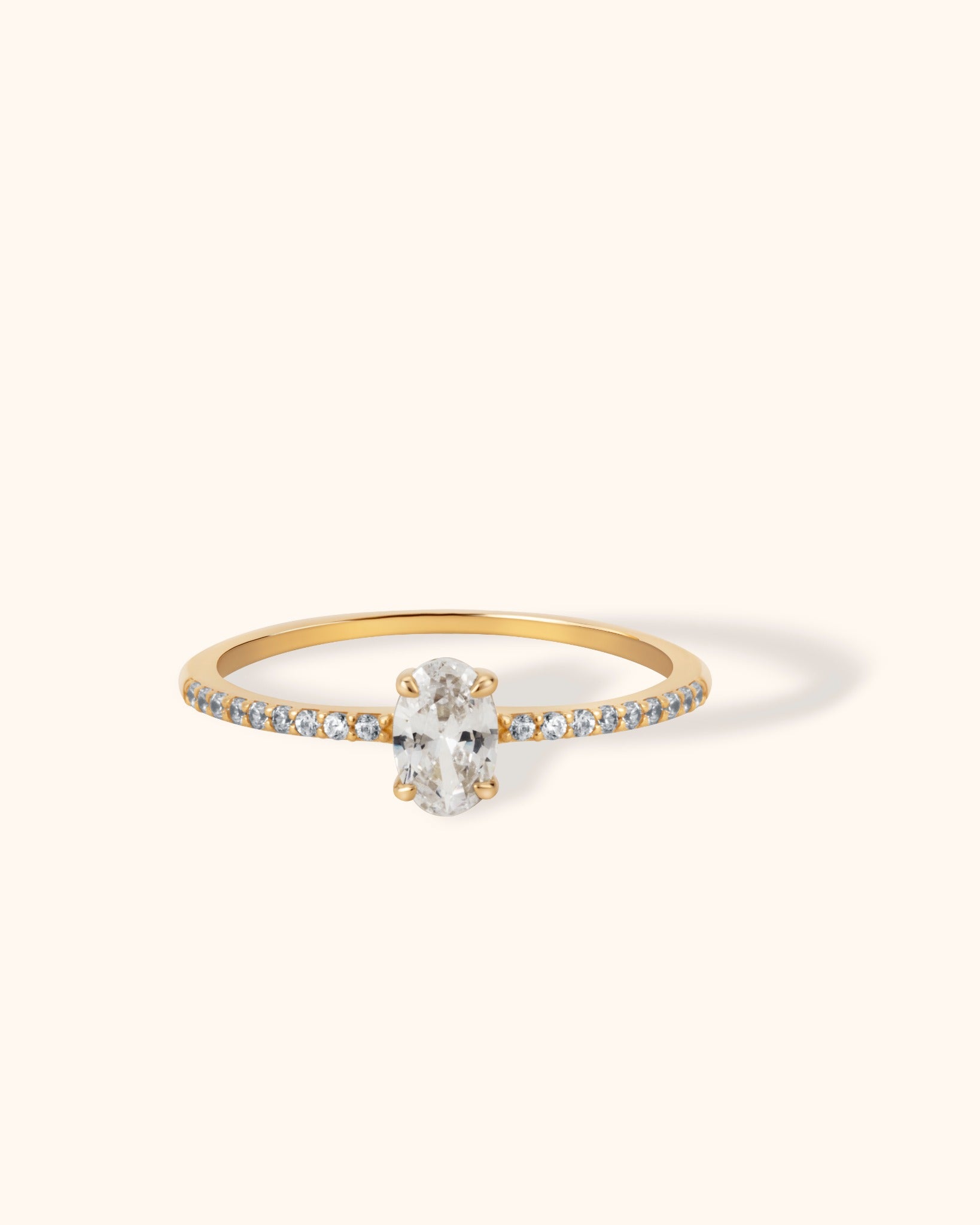 Elegant 14K gold ring featuring an oval cut white center stone with pavé side accents on a slim band