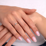 Delicate gold ring with pear-cut solitaire stone on woman’s hand wearing casual jeans, minimalist elegance