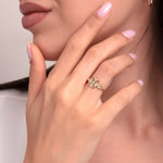Close-up of woman's hand wearing a 14K gold ring with pink enamel and marquise-cut clear stones in a geometric Art Deco design