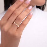 Close-up of a woman's hand wearing a 14K gold ring with polished matte disc shapes, designed for stacking