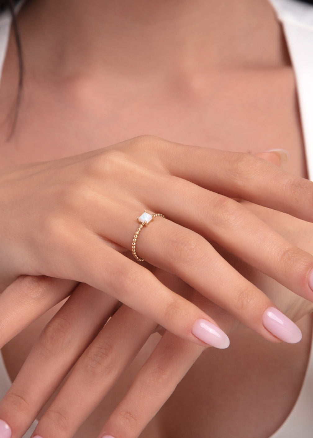 14K gold ring with round opal on a beaded band worn on a woman’s hand