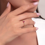 Woman wearing a 14K gold ruby solitaire ring with side stones on her ring finger, hand near chin