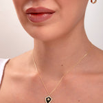 Elegant 14k gold shield pendant necklace with black enamel and star design on a woman’s neck

