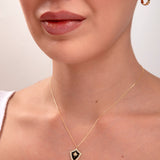 Elegant 14k gold shield pendant necklace with black enamel and star design on a woman’s neck

