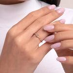 Close-up of a woman's hand wearing a 14K gold solitaire diamond ring with brilliant cut stone, styled with pastel pink nails and a white ribbed top.