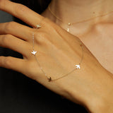 Minimalist 14K gold bracelet with flying bird charms on model’s wrist and hand