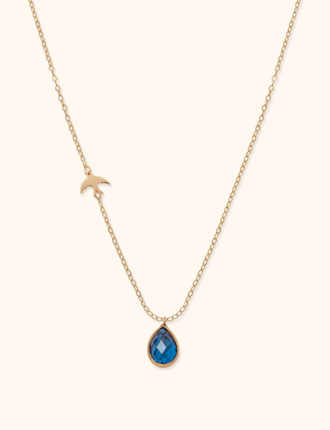 14K gold necklace with blue gemstone teardrop pendant and gold bird charm