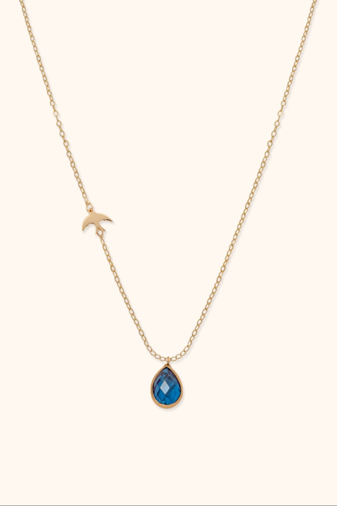 14K gold necklace with blue gemstone teardrop pendant and gold bird charm