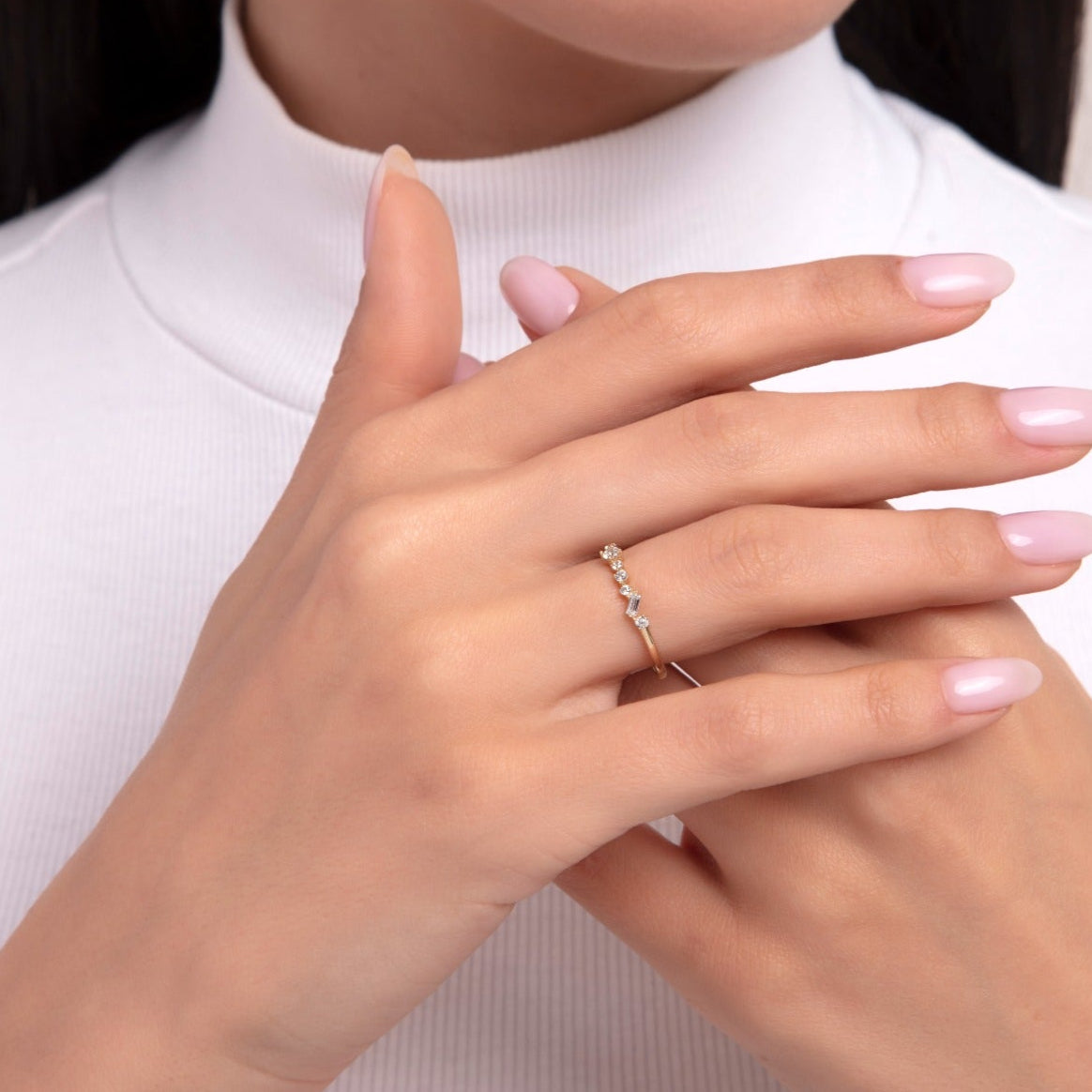 Close-up of a woman wearing a 14K gold ring with a tapered row of round-cut diamonds