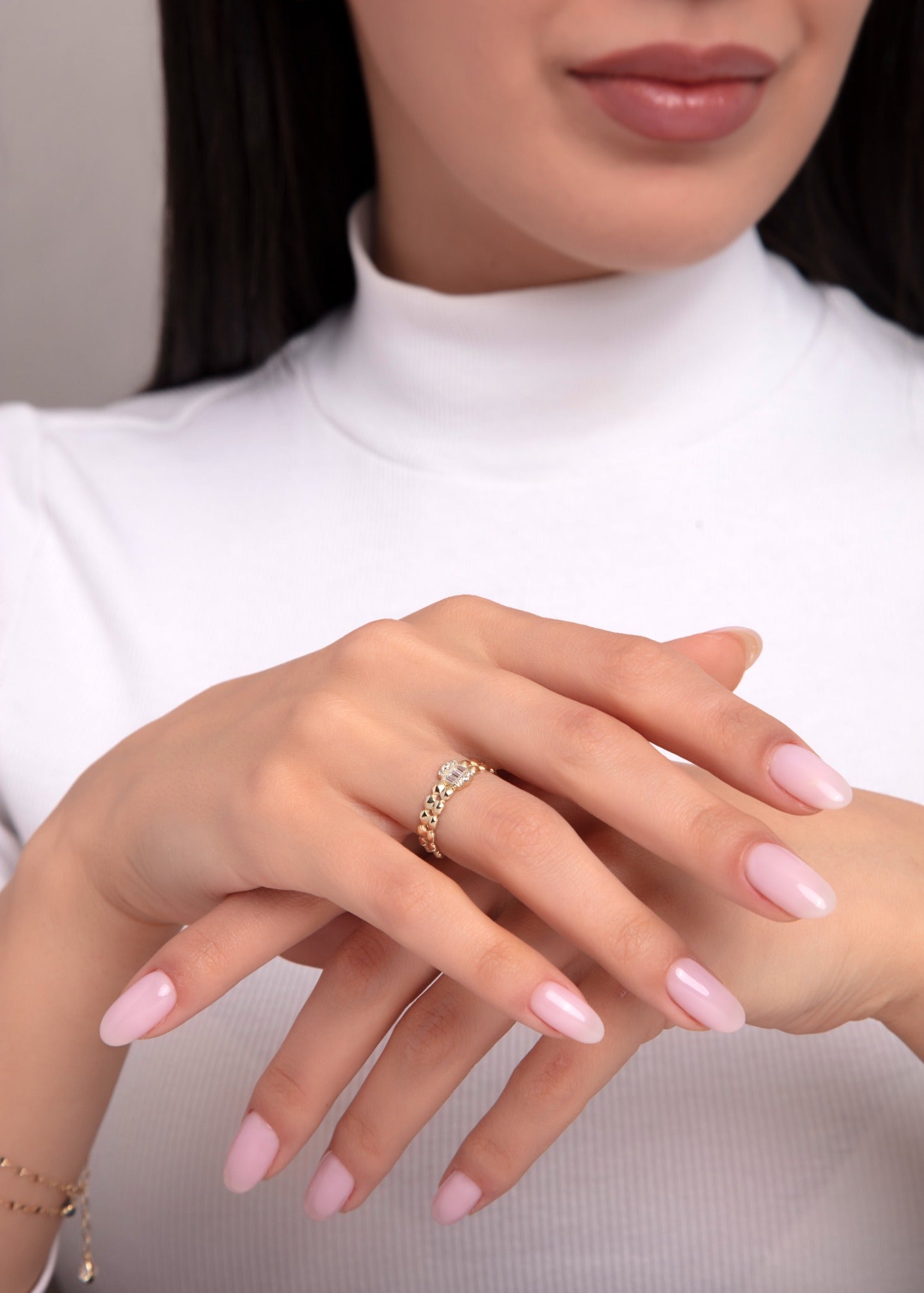 14K gold ring with braided texture and central baguette stone on woman’s hand