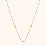 14K gold necklace with small textured bead accents on fine chain