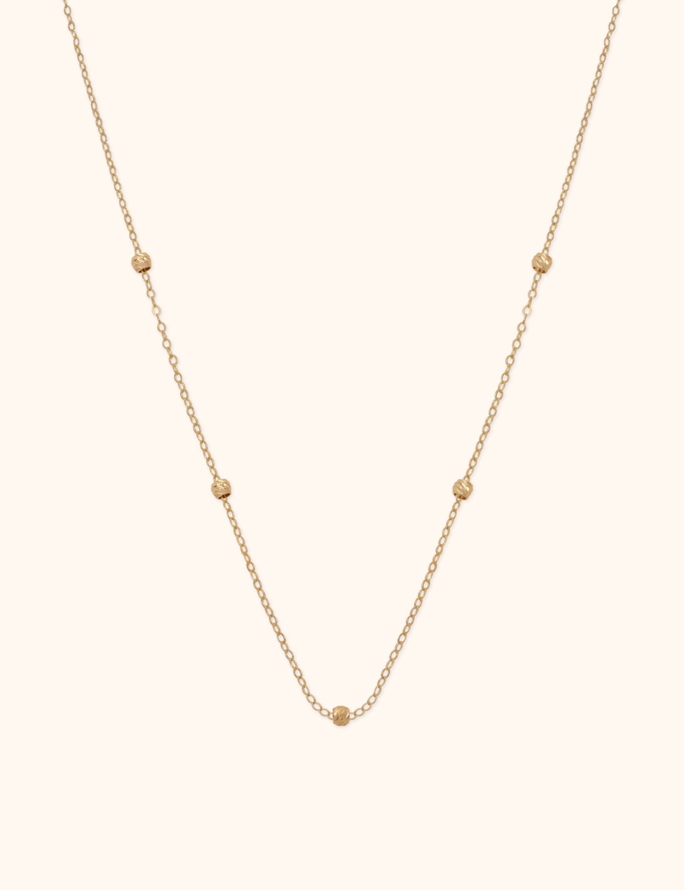 14K gold necklace with small textured bead accents on fine chain