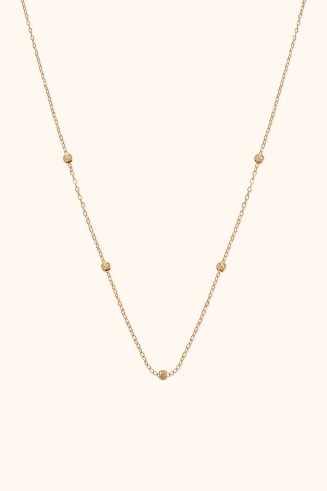 14K gold necklace with small textured bead accents on fine chain