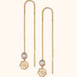 Delicate 14k gold threader earrings with faceted crystal and floral charm on light background

