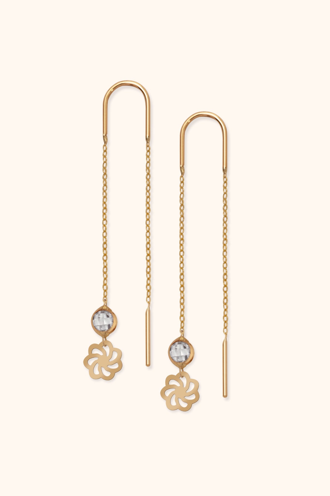 Delicate 14k gold threader earrings with faceted crystal and floral charm on light background

