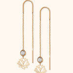 14k gold threader earrings with faceted crystal and lotus flower charm on light background

