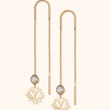 14k gold threader earrings with faceted crystal and lotus flower charm on light background

