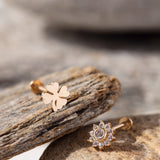 14K Gold Tragus Piercing Pair featuring a polished four-leaf clover stud and a sparkling CZ daisy flower stud – Charming cartilage earrings symbolizing luck and radiance, perfect for tragus or helix piercings."
