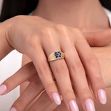 Model wearing a 14K gold ring with three vertical blue sapphires and side diamond accents on triple gold bands