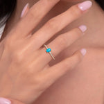 Close-up of woman's hand wearing a 14K gold ring with an oval turquoise stone and diamond accents