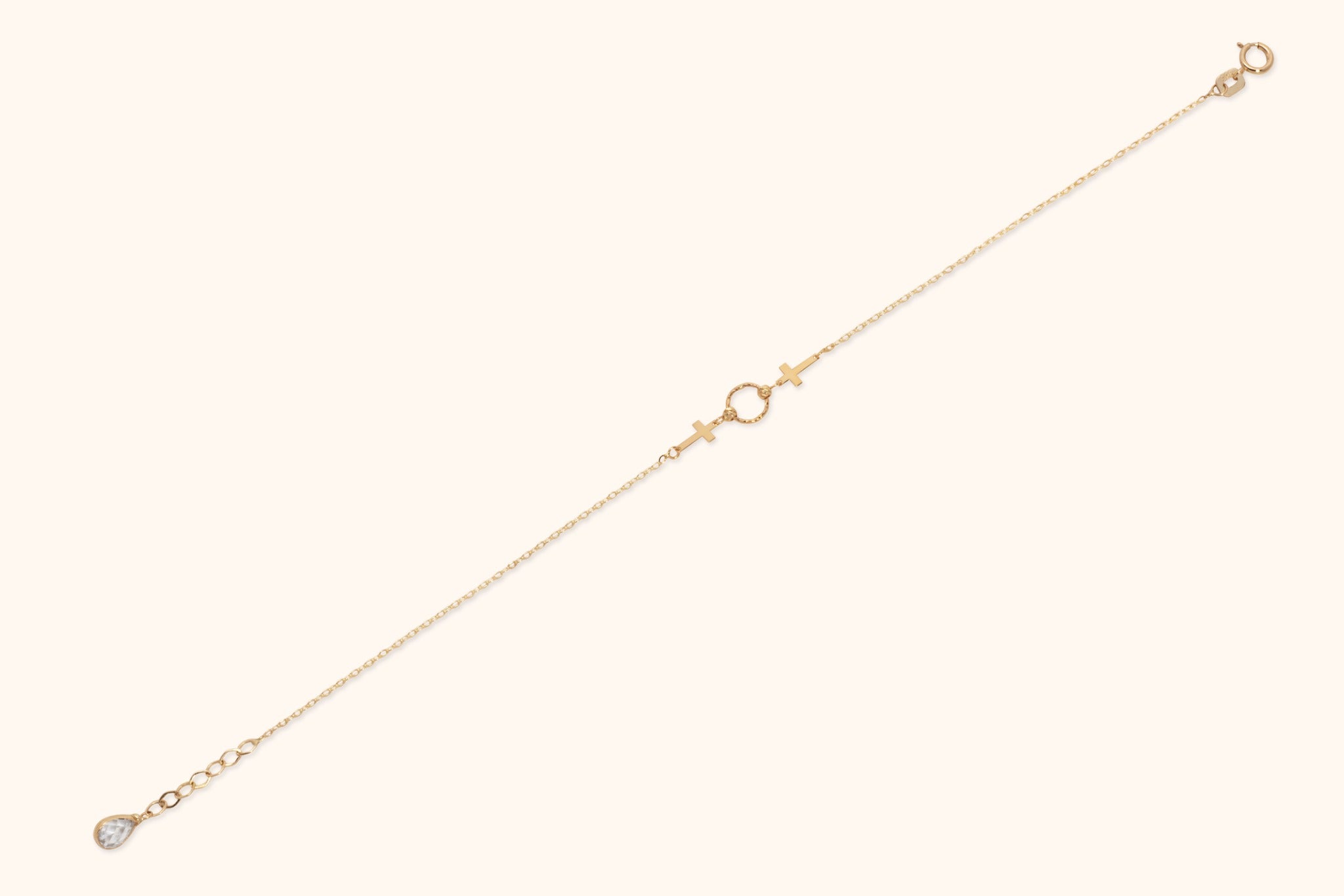 14K gold twin cross charm bracelet with center twisted circle on cream background