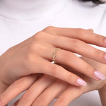 Close-up of a woman's hand wearing a dainty 14K gold twisted chain ring with a stylish link pattern