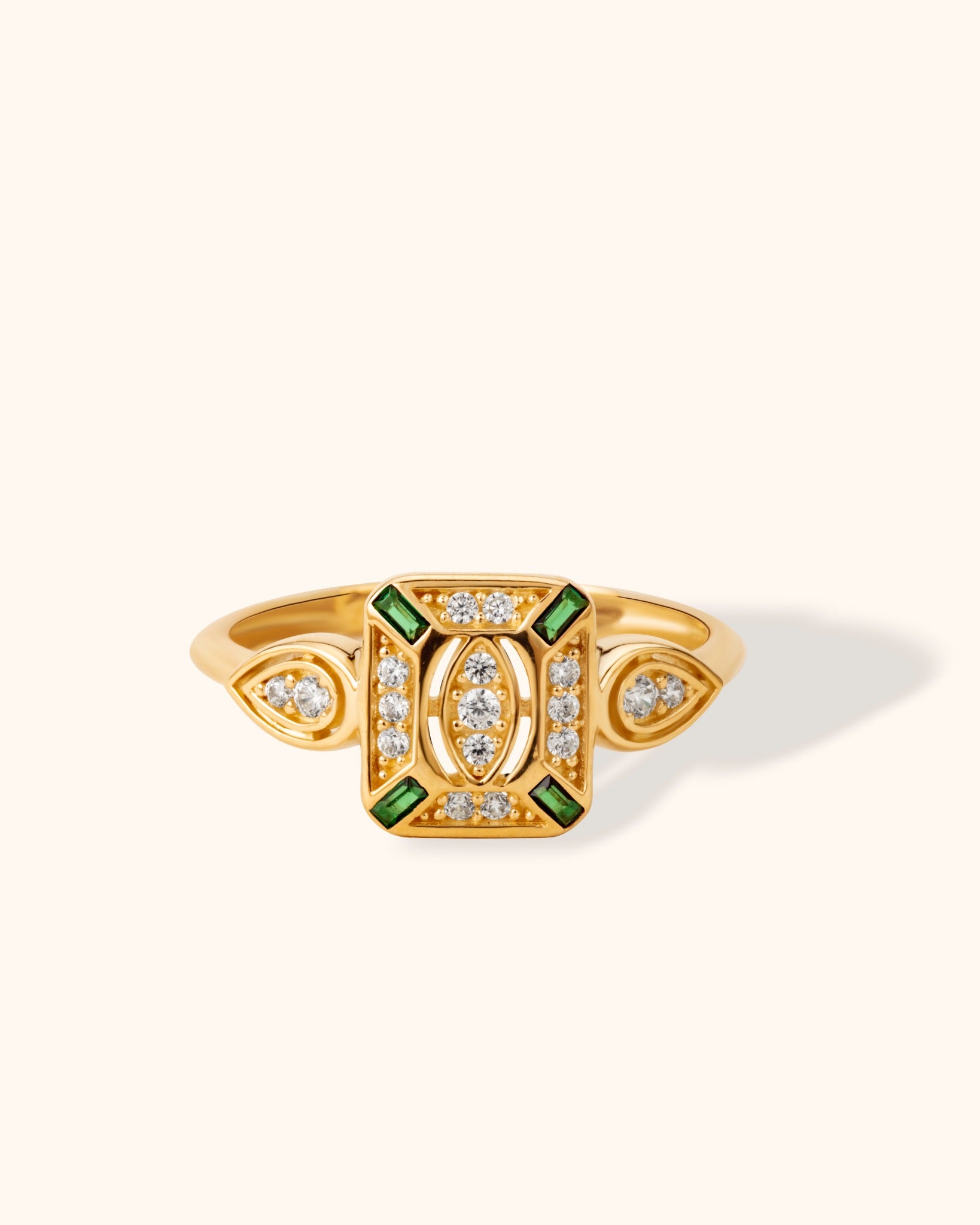 14K yellow gold ring with vintage rectangular design, green baguette stones, and white diamonds on cream background.