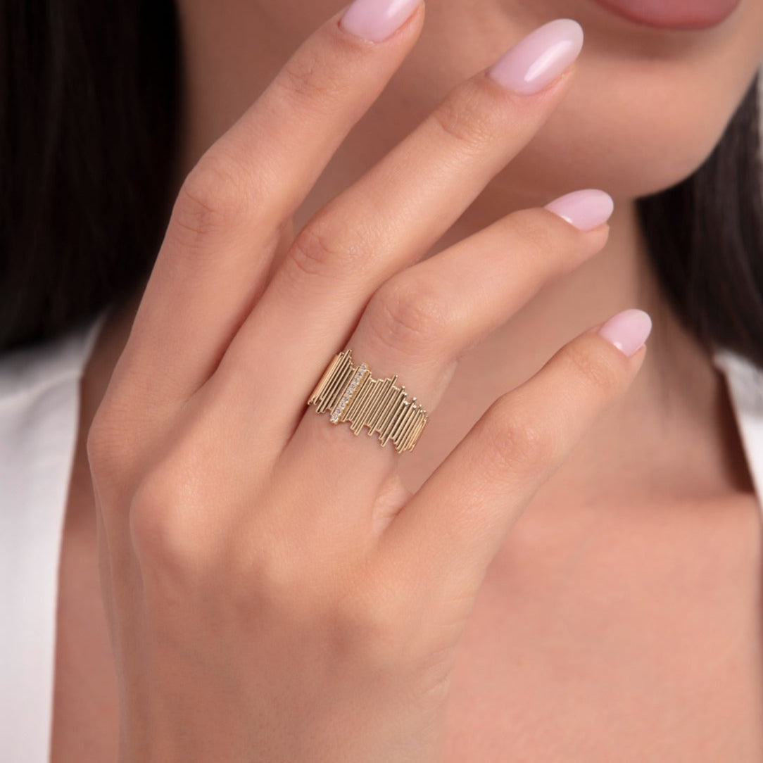Close-up of a woman's hand wearing a wide 14K gold ring with vertical baguette-style bar detailing in a contemporary design