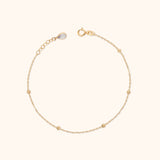 14K solid gold beaded bracelet with minimalist design on cream background