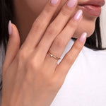 Close-up of a woman's hand wearing a 14K gold ring with a small white pearl – simple and elegant design