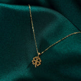 14K solid gold four-leaf clover necklace on green satin background, symbolizing luck and elegance