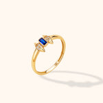 14K yellow gold stackable ring with a blue baguette-cut sapphire, round brilliant diamonds, and spike accents on a neutral background