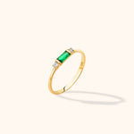 14K yellow gold stackable ring featuring an emerald-cut green baguette center and round diamond accents on a neutral background