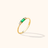 14K yellow gold stackable ring featuring an emerald-cut green baguette center and round diamond accents on a neutral background