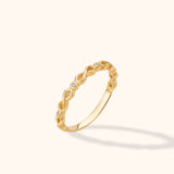 14K yellow gold infinity twist ring with pavé diamonds on a neutral background