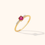 14K yellow gold stackable ring with a round pink sapphire center and linear tapered diamond accents on a neutral background