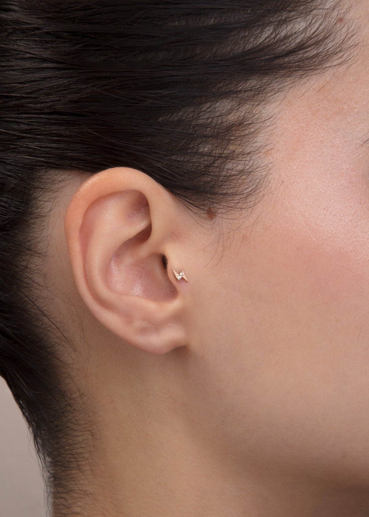 ear model wearing gold lightning bolt tragus earring cartilage piercing