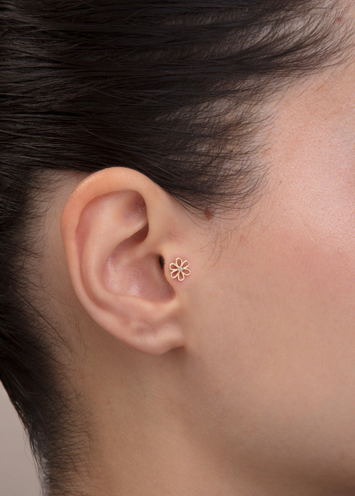 ear model wearing gold daisy tragus earring suitable for helix cartilage