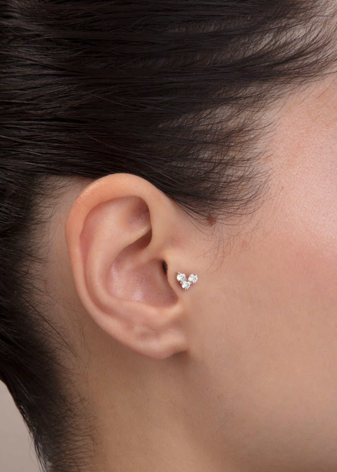 ear model wearing triple cz gold tragus earring cartilage piercing