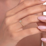 14K gold rope-style ring with emerald-cut clear zircon stone displayed on a woman's finger with soft pink manicured nails.