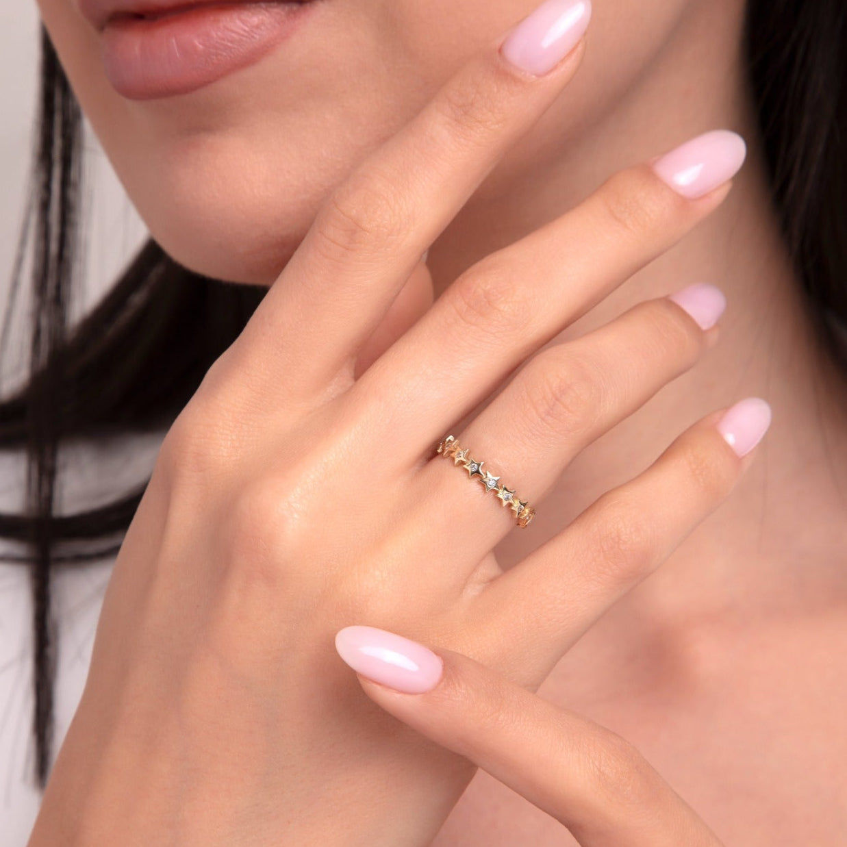14K gold star eternity ring with shimmering white stones, worn on a model's hand with pastel pink nails.