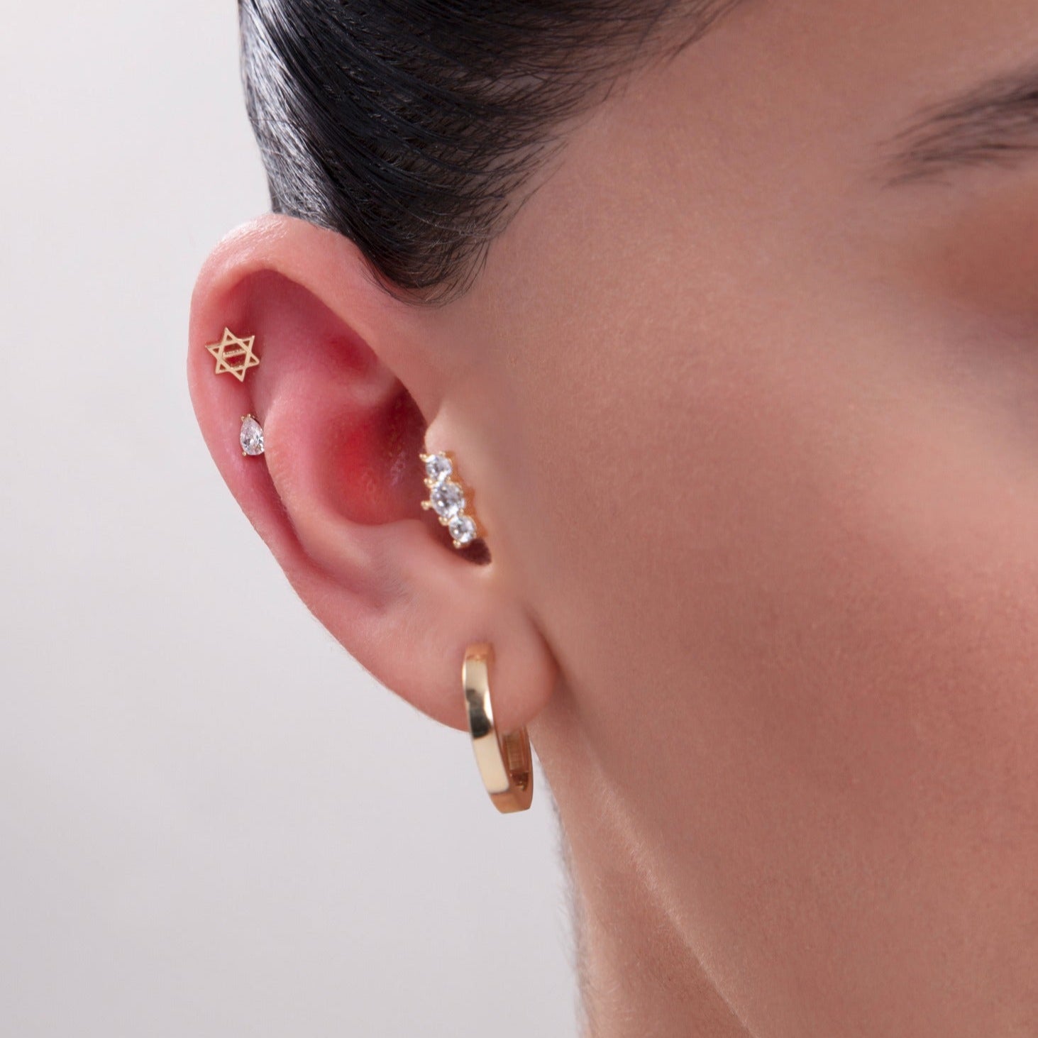14K gold triple cartilage earring stack with hexagram, teardrop and cluster studs – stylish multi-piercing ear styling with minimalist hoop.