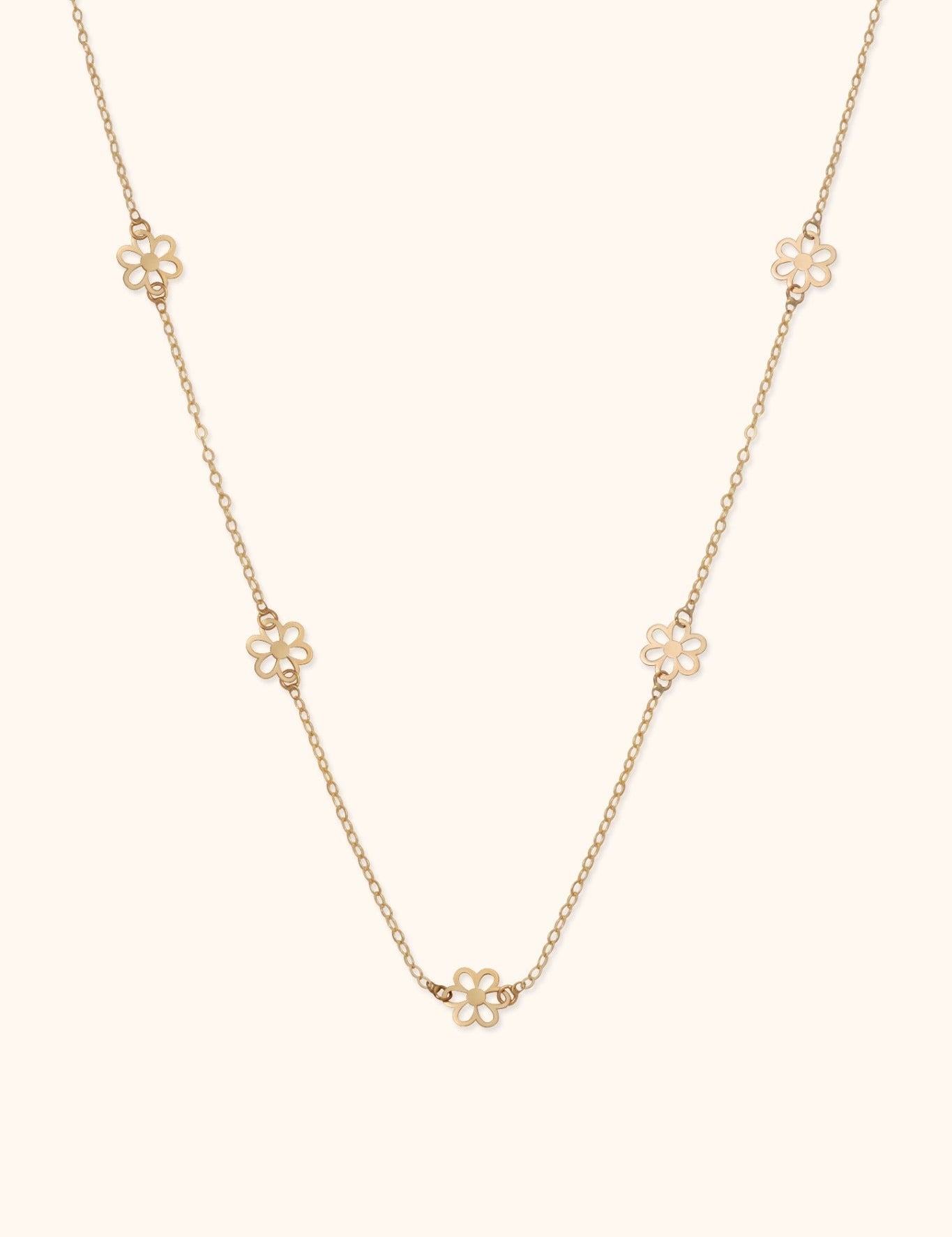 Gold-toned fine chain necklace with five open-petal flower motifs spaced along the chain, shown on a cream background.