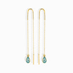 Pair of gold-toned threader earrings with long chains, slim bar ends and faceted blue teardrop pendants on a white background.