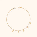 Fine gold-colored chain bracelet with five dangling cross charms, a round clasp, and an extension chain with a teardrop-shaped charm.